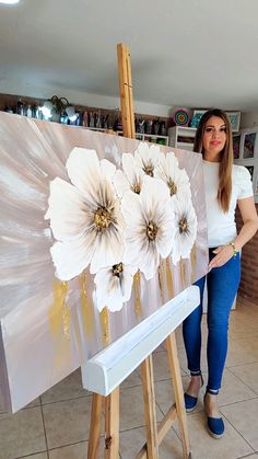 a woman standing in front of an easel with flowers on it