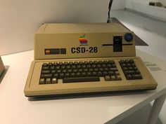 an old computer sitting on top of a white table next to a box with the word csd - 29 printed on it