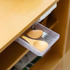 a wooden spoon and fork in a plastic container under a desk drawer with utensils