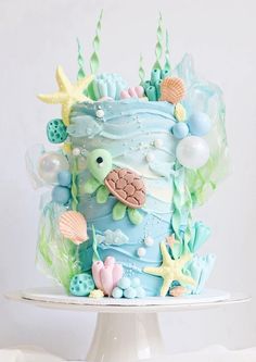 there is a cake decorated with sea animals on the top and under water bubbles, starfish, seashells, and pearls