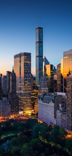 the city skyline is lit up at night, with skyscrapers in the foreground