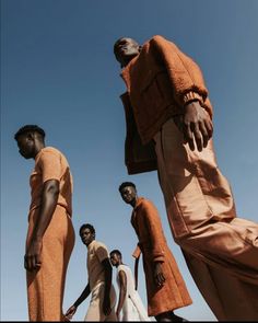 four men in orange clothing standing next to each other with their hands on their hipss