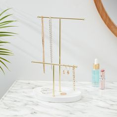 a white counter top with gold jewelry on it and a plant in the corner next to it