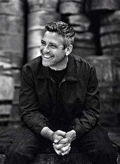 a man sitting on top of a wooden bench next to stacks of beer barrels in black and white