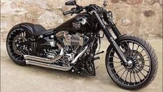 a black motorcycle is parked in front of a stone wall and has chrome rims