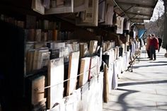 people walking down a sidewalk lined with books