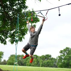 a young boy is hanging from a rope in the air with his hands and feet