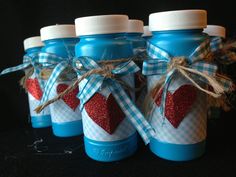 four blue glass bottles with red hearts tied to the top and white caps on them