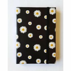 a black notebook with white and yellow daisies printed on it, sitting against a white background