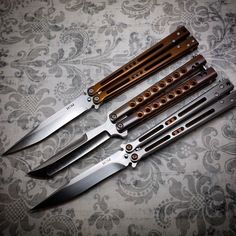 five knives are sitting next to each other on a tablecloth with floral designs in the background