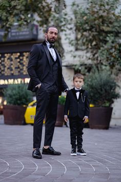 a man in a tuxedo standing next to a little boy