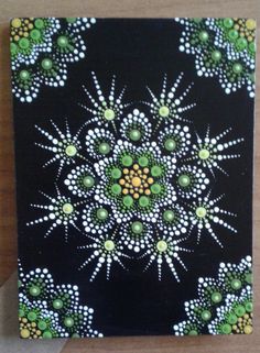 a black square with green and white designs on it's sides, sitting on a wooden surface