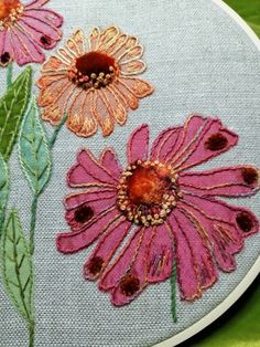 a close up of a embroidery on a piece of cloth with flowers in the center