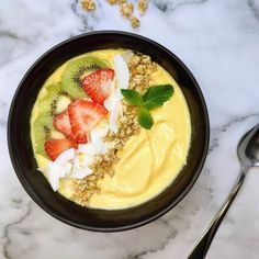 a bowl filled with yogurt and fruit on top of a marble countertop