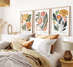 a bed with pillows and blankets on top of it next to two pictures hanging above the headboard