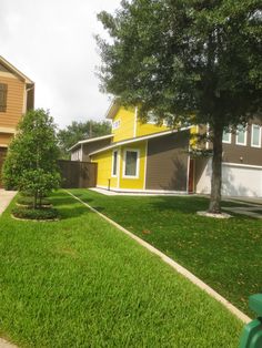 a yellow house with green grass and trees