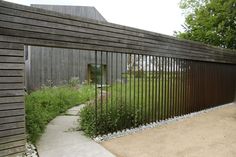 a wooden building with a metal fence on the outside and grass growing in between it