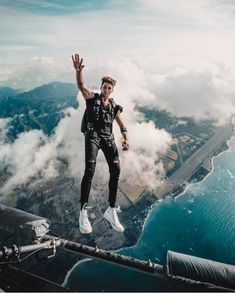 a man in black shirt and white sneakers standing on the edge of a high rise