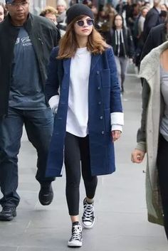 two people walking down the street, one wearing black and white converses while the other wears blue