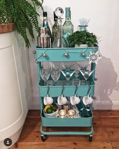 a blue cart filled with lots of dishes and drinks on top of a wooden floor