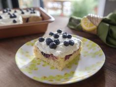 a piece of cake with blueberries on top is sitting on a plate next to a baking pan