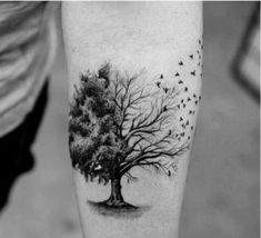 a black and white photo of a tree with birds flying around it on the leg