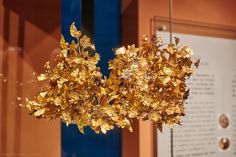 a gold leafy object is on display in a museum