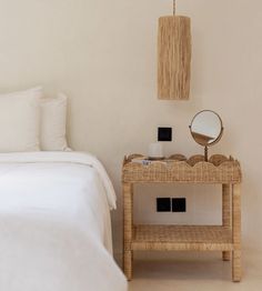 a bedroom with a wicker table and mirror on the wall next to a bed