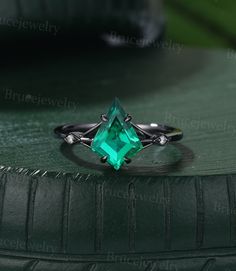 an emerald colored ring sitting on top of a green surface