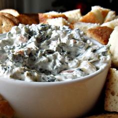 a white bowl filled with dip surrounded by bread