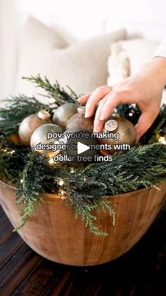 someone placing ornaments in a wooden bowl on a table