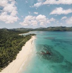 an aerial view of the beach and ocean with palm trees in the foreground, surrounded by blue water