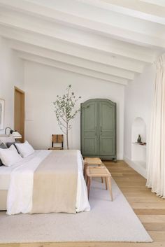 a bedroom with white walls and wood flooring has a large bed in the center