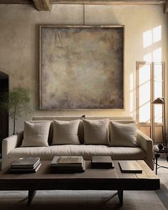 a living room filled with furniture and a large painting on the wall above it's coffee table