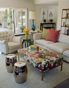 a living room filled with lots of white furniture and colorful pillows on the couches