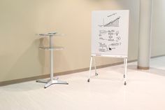 a white board with drawings on it next to a stand in an empty room,