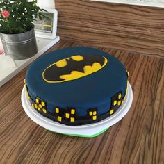 a batman themed cake sitting on top of a table next to a potted plant