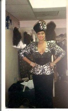 a woman standing in front of a mirror wearing a black and white outfit with feathers on it