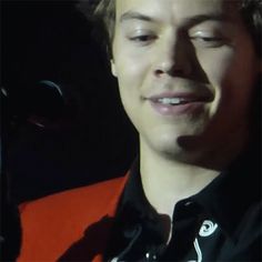 a close up of a person wearing an orange vest and smiling at the camera with his eyes closed