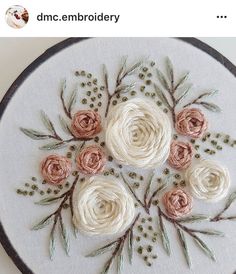 a close up of a embroidery on a hoop with flowers and leaves in the center