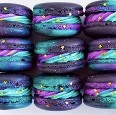 purple and blue macaroons with stars painted on them are stacked in a row