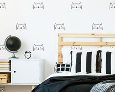 a bed room with a neatly made bed and cat wall decals