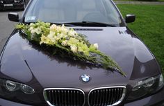 flowers are placed on the hood of a black car in front of some parked cars