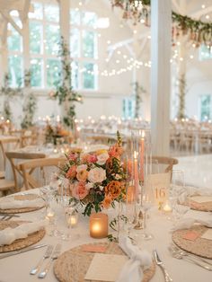 a table set with place settings and candles for an elegant wedding reception in a white walled room