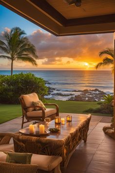 an outdoor living area with wicker furniture and candles lit on the table in front of the ocean