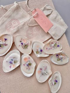 seven porcelain spoons with dried flowers on them and a bag in the back ground