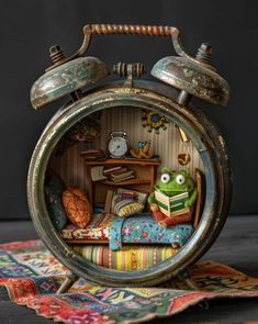 an alarm clock sitting on top of a rug next to a table with books and pillows