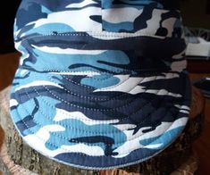 a blue and white camouflage hat sitting on top of a tree stump in front of a computer keyboard