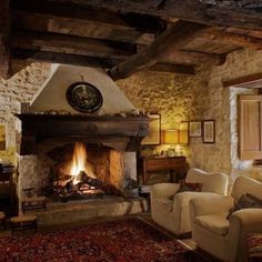 a living room filled with furniture and a fire place in the middle of a stone wall