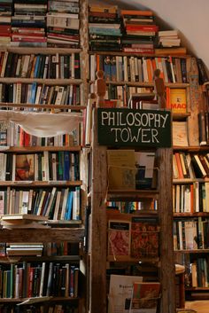 a bookshelf filled with lots of books next to a wooden sign that reads philosopy tower